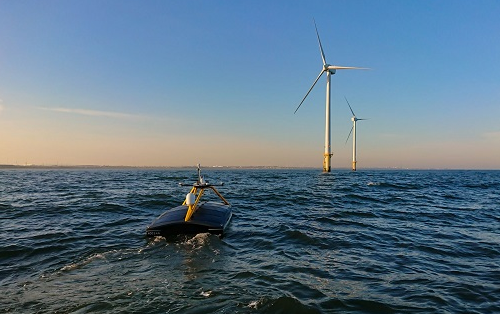 Autonomous marine vessel near offshore wind turbines on calm sea