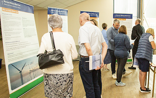 People reading informational posters about Morven Offshore Wind Farm indoors