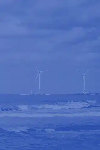 Offshore wind turbines in the ocean under a cloudy sky