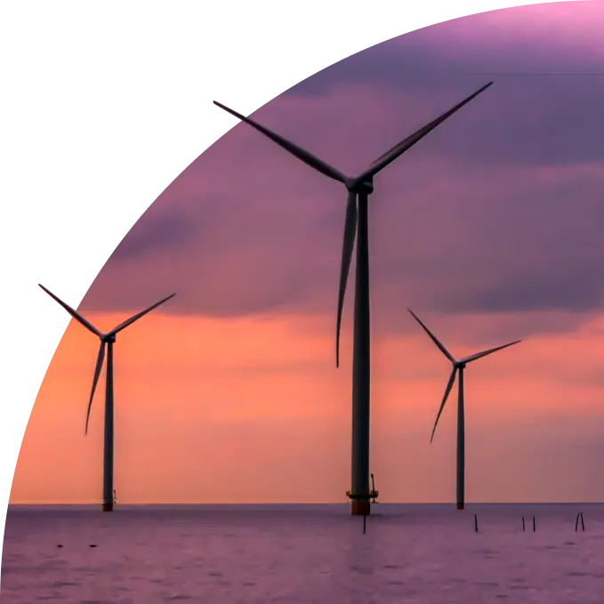 Three offshore wind turbines at sunset with purple and orange sky