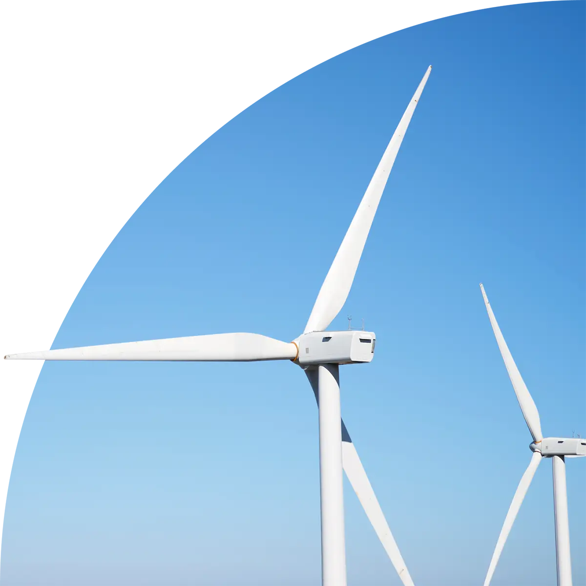 Close-up of two white wind turbines against a clear blue sky